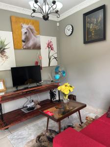a living room with a desk with a television and a clock at Jobe Guesthouse in Pietermaritzburg