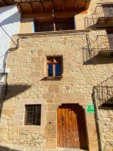 een stenen gebouw met een deur en twee ramen bij CASA MIRIAM in La Iglesuela del Cid