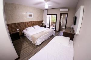 - une chambre avec un grand lit blanc et un balcon dans l'établissement Hotel Fazenda Horizonte Belo, à Brumadinho