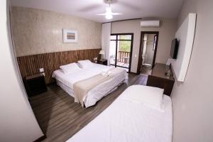 um quarto com uma grande cama branca e uma varanda em Hotel Fazenda Horizonte Belo em Brumadinho