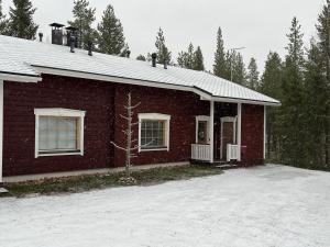uma casa de tijolos vermelhos com neve no chão em Levin Ruska B em Kittilä