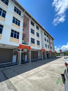 a large white building with cars parked in front of it at KW HOMESTAY CASA UNO APARTMENT in Sandakan