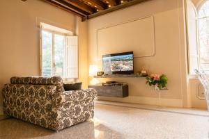 a living room with a chair and a flat screen tv at Noble Floor - Luxury Apartments in Lucca