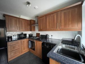 a kitchen with wooden cabinets and a black refrigerator at The Haven in Hornsea Town Centre in Hornsea
