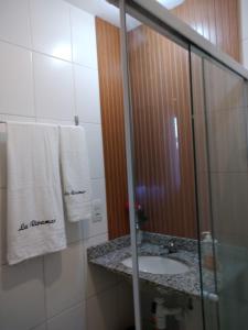 uma casa de banho com um lavatório e uma cabina de duche em vidro. em Riviera CONDOMINIO Clube - BOA VIAGEM torre natura ap 1103 no Recife