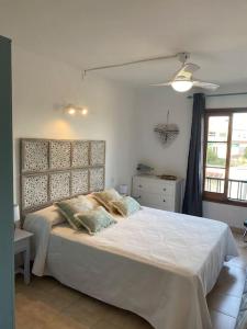 a bedroom with a large white bed and a window at sa caleta blava in Cala en Blanes