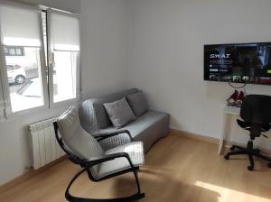 een woonkamer met een bank, een stoel en een bureau bij Precioso apartamento con patio in Zamora