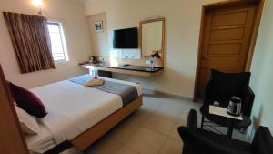 a bedroom with a bed and a desk and a chair at Hotel Aishwaryaa in Erode