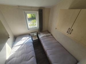 - 2 lits dans une petite chambre avec fenêtre dans l'établissement Gezellig chalet op een prachtige plek in Drenthe met vrij uitzicht, à Tynaarlo