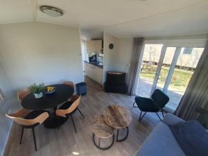 een woonkamer met een tafel en stoelen en een bank bij Gezellig chalet op een prachtige plek in Drenthe met vrij uitzicht in Tynaarlo