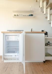 an empty white refrigerator in a kitchen with stairs at La Risorta in Cesiomaggiore
