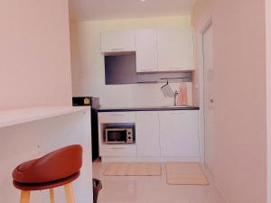 a small kitchen with white cabinets and a red chair at 29th floor Studio, Cozy Workplace, Long stay, wide space in Amphoe Phra Khanong