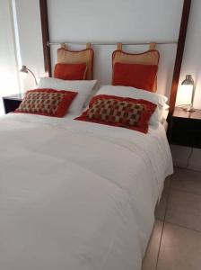 Una cama blanca con dos almohadas rojas. en Luminoso y acogedor departamento en Recoleta en Buenos Aires