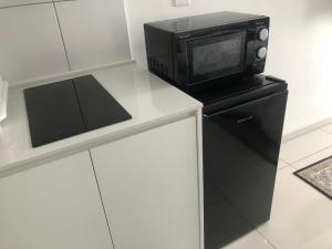 a microwave sitting on top of a black refrigerator at Horizon Suites poolview near KLIA in Sepang