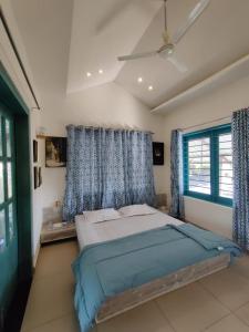 a bedroom with a large bed with blue curtains at Osaree Agro and Art Hub in Kolhapur