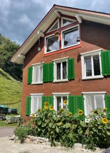 a house with green and white windows and flowers at Private Room in an old Farmhouse near Vaduz in Sevelen
