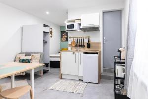 małą kuchnię z białą lodówką i stołem w obiekcie Studio cosy au coeur de l'Ecusson - Arènes à 2 min w mieście Nîmes +18 zdjęć