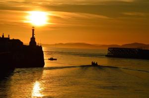 a sunset over the ocean with a lighthouse and people in a boat at Blue Anchor House in Maryport