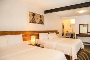 a hotel room with two beds and a bathroom at Villa Maria Hotel in Valle de Bravo