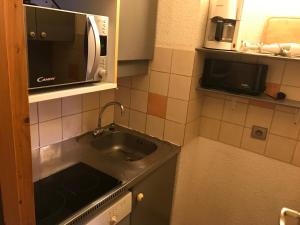 eine kleine Küche mit einer Spüle und einer Mikrowelle in der Unterkunft appartement ski au pied 