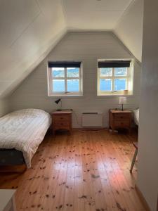 a attic bedroom with two beds and two windows at Spacious apartment with view over the trondheimfjord in Vangshylla