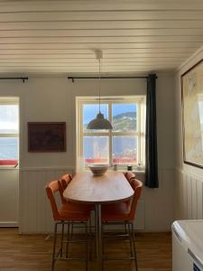 a dining room with a table and chairs and two windows at Spacious apartment with view over the trondheimfjord in Vangshylla