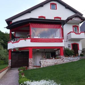 a red and white house with a balcony at Villa Jelena Mavrovo in Mavrovo