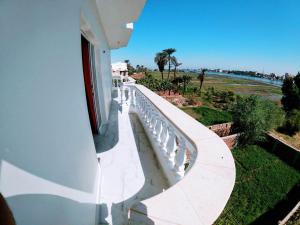 ein weißes Gebäude mit einer Bank am Meer in der Unterkunft Set ma'at in Luxor