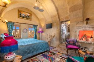 a bedroom with a blue bed and a fireplace at Cappadocia Splendid Cave Hotel in Ortahisar