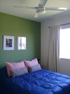 1 dormitorio con 1 cama azul y ventilador de techo en Casas Tomillo Silvestre en Sierra de la Ventana