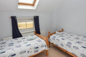 two twin beds in a room with a window at 12A Solent Landing direct beach access in Bembridge