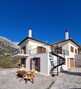 a large white house with a staircase and a table at Panorama in Arachova