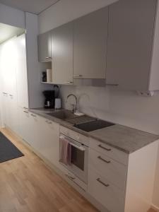 een witte keuken met witte kasten en een wastafel bij New&Easy apartment in the center in Turku