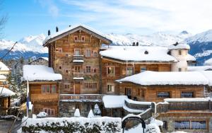 クランにあるHostellerie du Pas de l'Ours "Relais et Châteaux"の山々を背景にした雪の丸太小屋