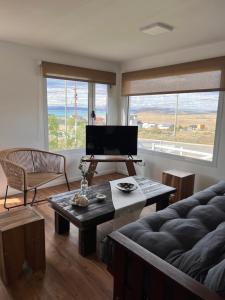 ein Wohnzimmer mit einem TV, einem Sofa und einem Tisch in der Unterkunft Cabañas del lago in El Calafate