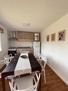 a kitchen with a wooden table and white chairs at Cabañas del lago in El Calafate +13 photos