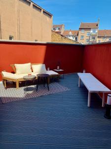 un patio con bancos y mesas en una pared roja en Chez Tess, en Metz