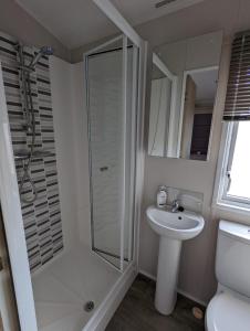uma casa de banho com um chuveiro e um lavatório. em BEAUTIFUL LUXURY Caravan HAVEN LITTLESEA STUNNING VIEWS Sleeps 6 em Weymouth