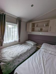 Duas camas num pequeno quarto com uma janela em BEAUTIFUL LUXURY Caravan HAVEN LITTLESEA STUNNING VIEWS Sleeps 6 em Weymouth