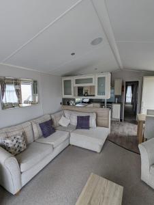 BEAUTIFUL LUXURY Caravan HAVEN LITTLESEA STUNNING VIEWS Sleeps 6 في ويماوث: غرفة معيشة مع أريكة وطاولة