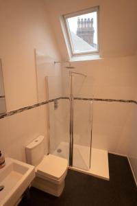 y baño con ducha, aseo y lavamanos. en Modern 2nd floor 1 bed apartment in the heart of, en Llandudno