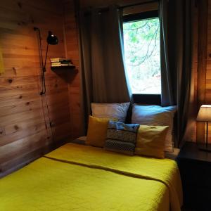 a bedroom with a yellow bed with a window at CHALET Chataigne ETAPEBOISEE in Fumay