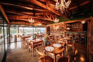 a restaurant with wooden tables and chairs and a chandelier at Pipas Terroir - Vale dos Vinhedos - Pousada Temática in Bento Gonçalves