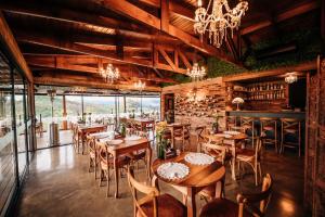 un restaurant avec des tables et des chaises en bois et un lustre dans l'établissement Pipas Terroir - Vale dos Vinhedos - Pousada Temática, à Bento Gonçalves