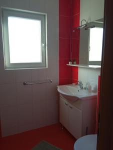 a red bathroom with a sink and a window at Apartments Tomić in Vodice
