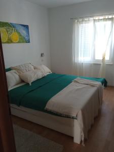 Un dormitorio con una cama con sábanas verdes y una ventana en Apartments Tomić en Vodice
