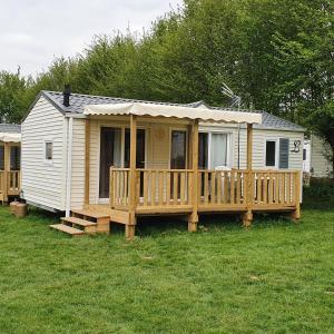 una casa pequeña con porche y terraza en Camping Les Sources Liencourt en Liencourt