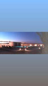due immagini di un edificio con luci accese di Riad Caravasar a Merzouga