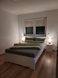 a bedroom with a large bed with two windows at Ferienwohnung Hanek in Annweiler am Trifels