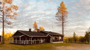 Kätkä Lake Lodge في Tervola: منزل خشبي مع شرفة وشجرة
